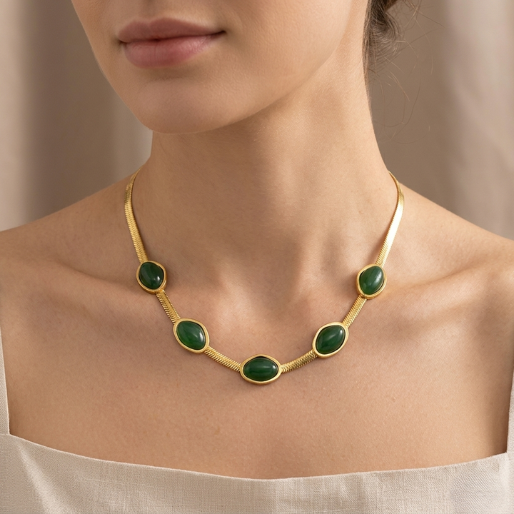 Elegant emerald green gold statement necklace with oval gemstone accents worn by a woman, chic minimalist choker jewelry for women with luxury-inspired design.