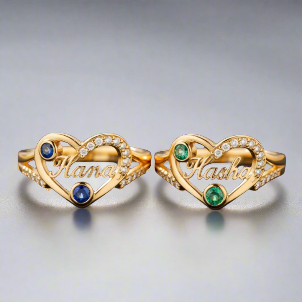 Two gold heart-shaped rings with gemstones on a gray background