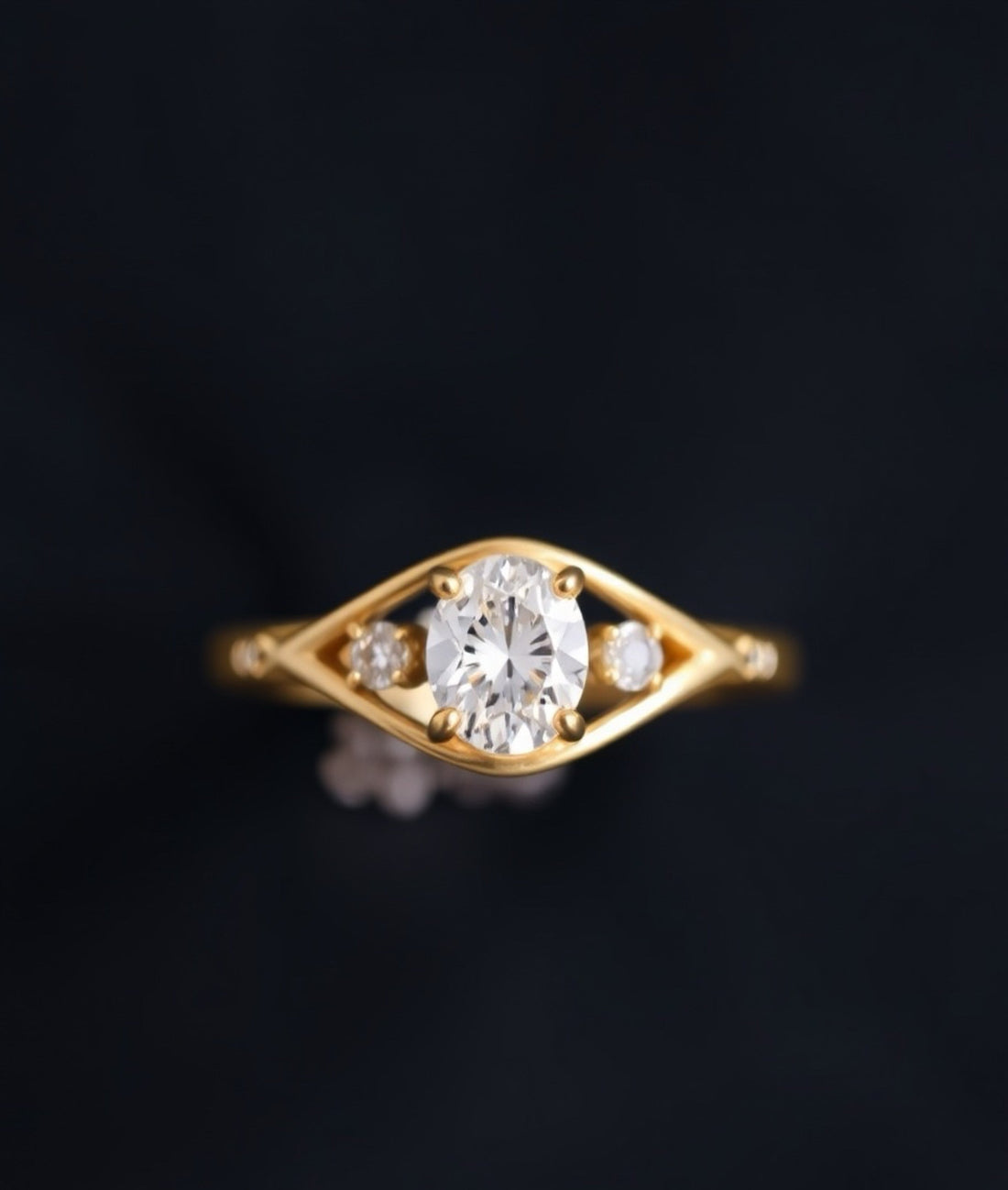 Oval cut diamond engagement ring set in yellow gold, featuring a central oval diamond with two smaller side stones on a sleek, modern band.