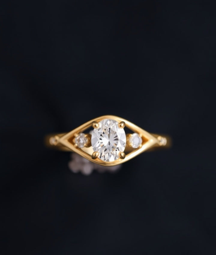 Oval cut diamond engagement ring set in yellow gold, featuring a central oval diamond with two smaller side stones on a sleek, modern band.