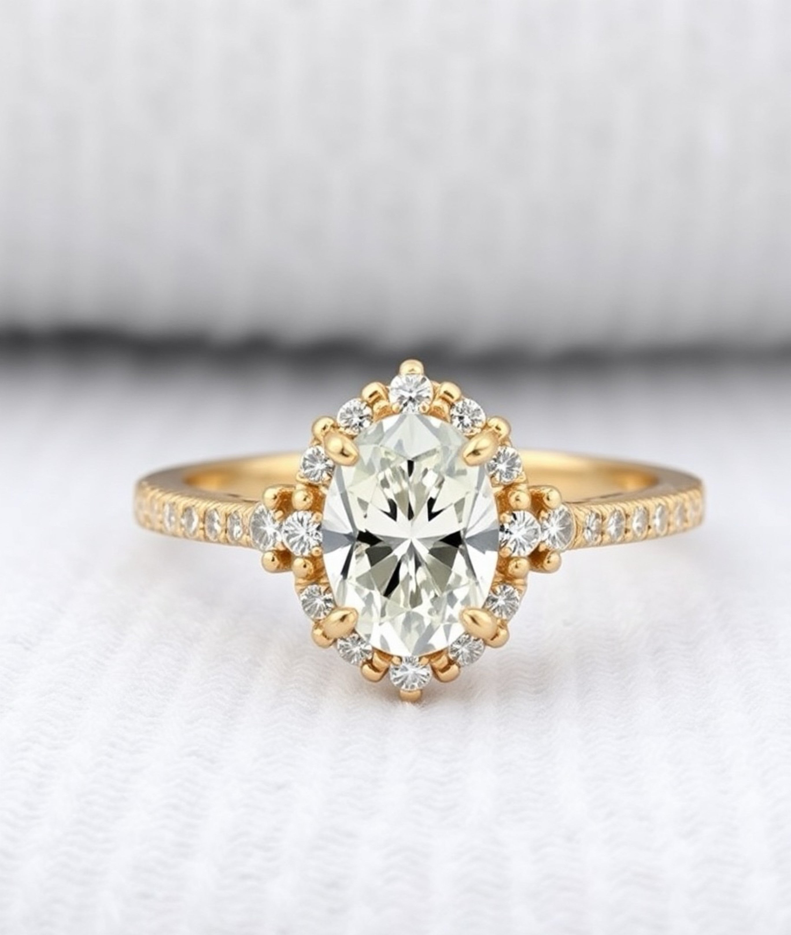 Oval cut diamond halo engagement ring in yellow gold featuring a sparkling oval center stone surrounded by a delicate diamond halo, elegant bridal jewelry design.
