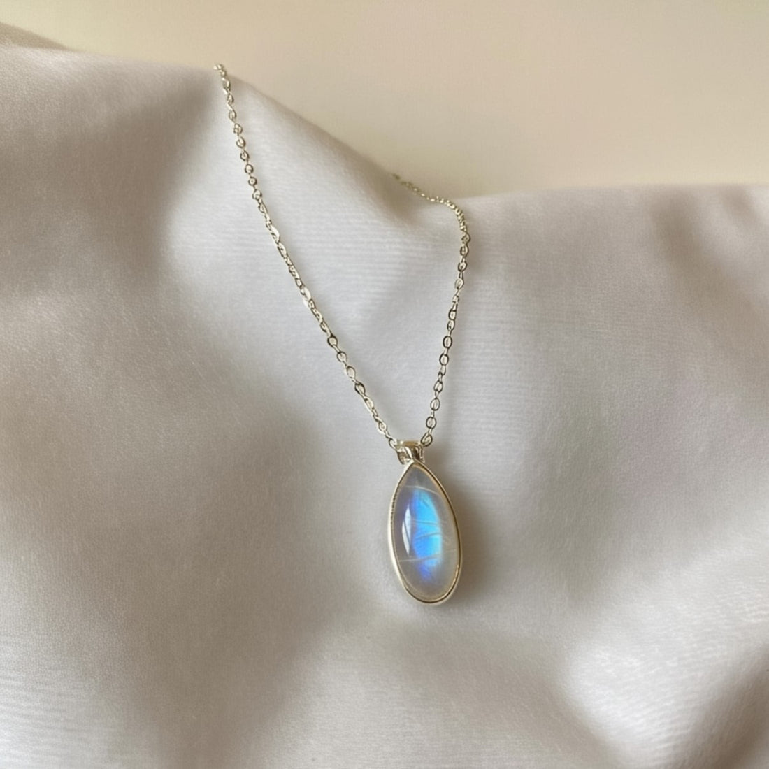 Natural moonstone jewelry piece glowing with blue sheen on soft white background